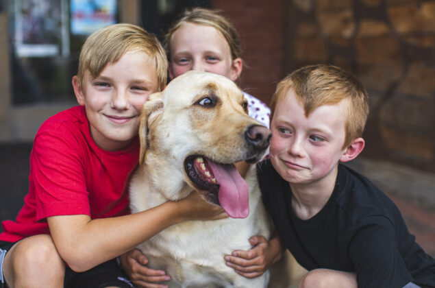 Three children snuggle a dog
