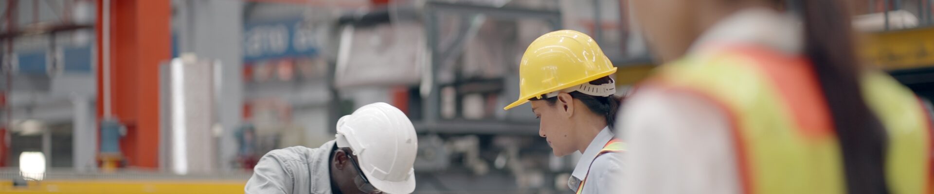 Engineers or production line worker wearing protective uniforms inspect machinery in the manufacturing factory.