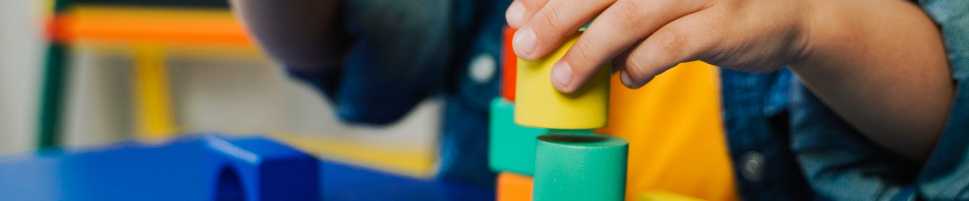 Kid hands playing with wood toys at preschool for development therapy