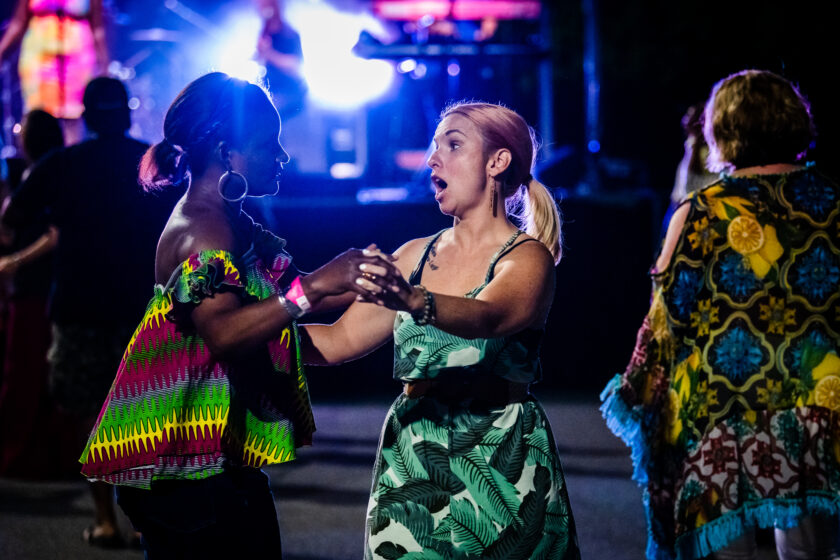 Black and white woman dance together at a street concert