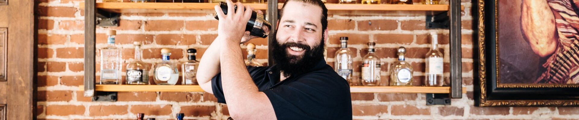 Bartender behind a bar shaking a cocktail