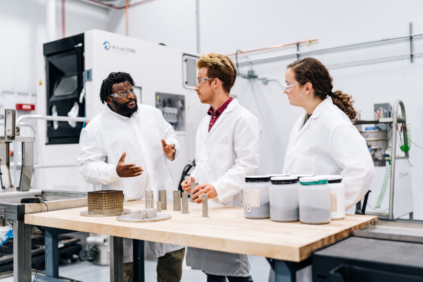 A black man educating a young man and woman in a lab environment