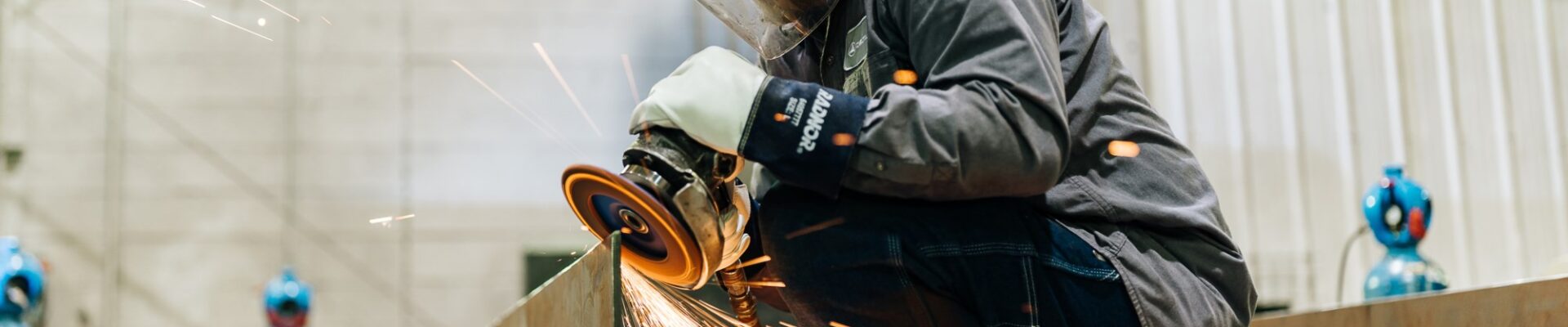 Man crouched on table using welding machine with sparks fying.