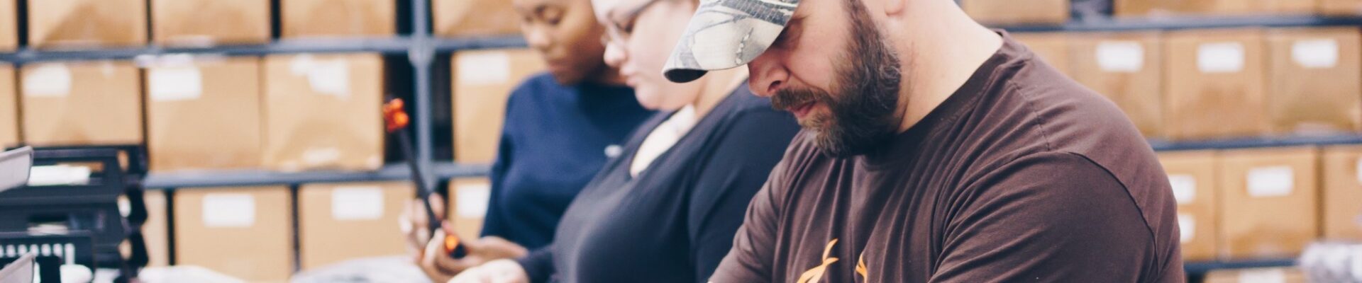 Closeup of a male and two females working an assembly line.