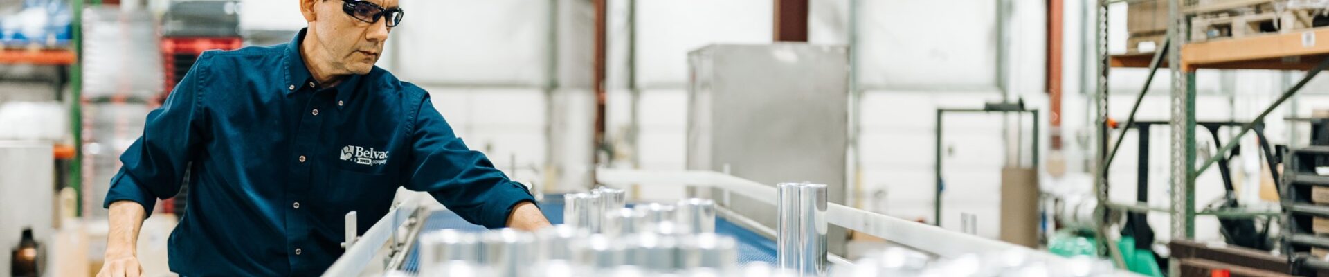 A worker at Belvac stands alongside machinery that manufactures metal cans.