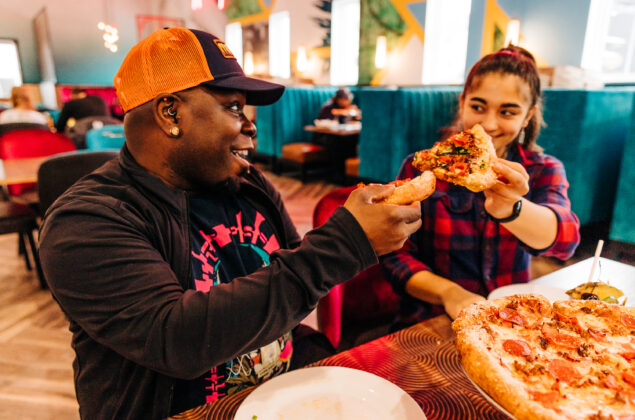 BIPOC couple toast with pizza at a Mellow Mushroom in the City of Lynchburg, VA