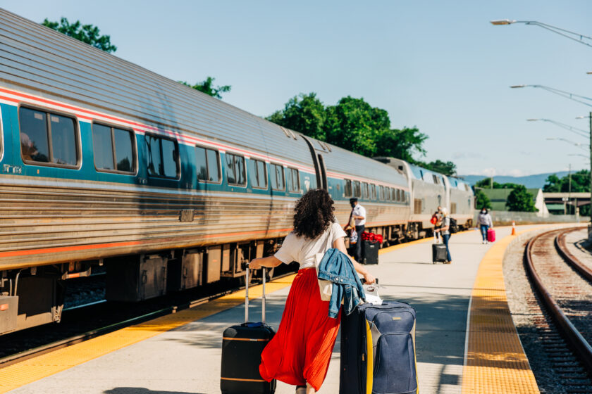 A woman runs to a train on an outdoor train platform.