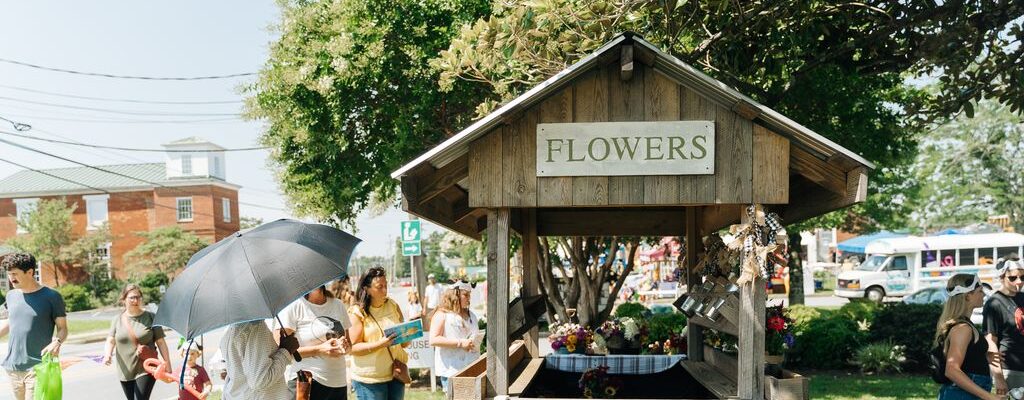 People surround a flower stand at an outdoor market