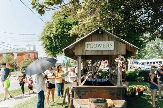 People surround a flower stand at an outdoor market