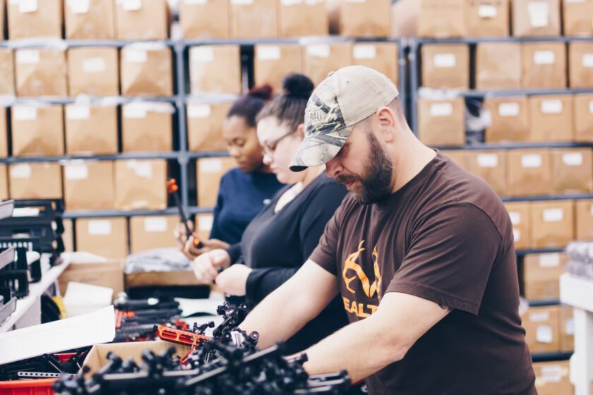 Tru Ball Archery employees work together on equipment.