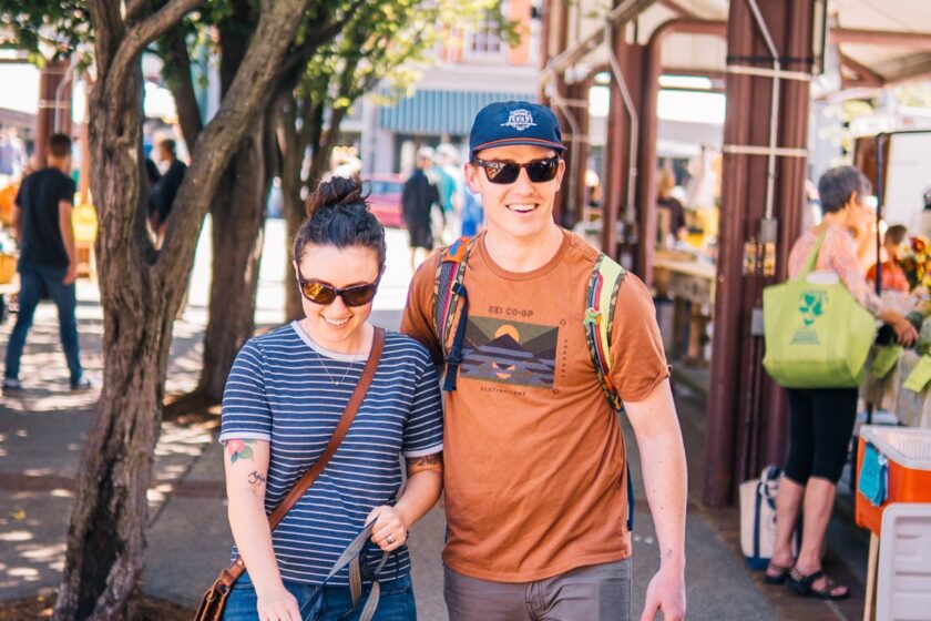 A young couple and their dog attend an ourdoor market.