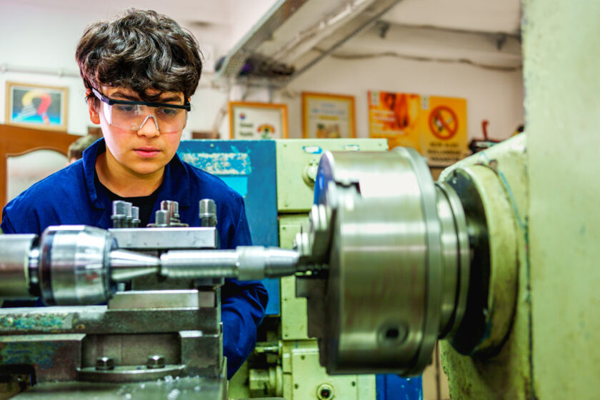 Student operating a lathe in a workshop.