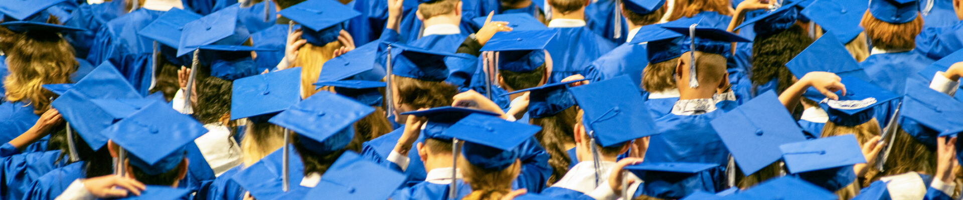 Student audience wearing grown and mortarboard hats during High School Graduation Ceremony