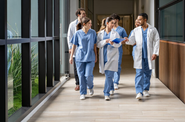 Happy group of Latin American medical students walking in the corridor at the hospital while talking