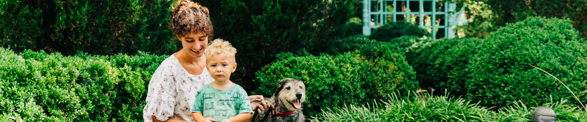 A woman, child, and dog hang out in a garden.