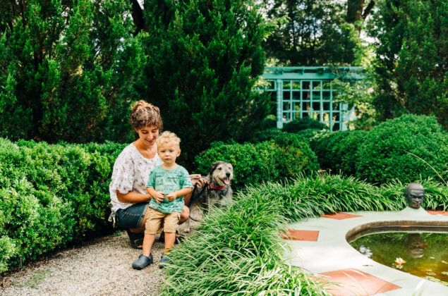 A woman, child, and dog hang out in a garden.