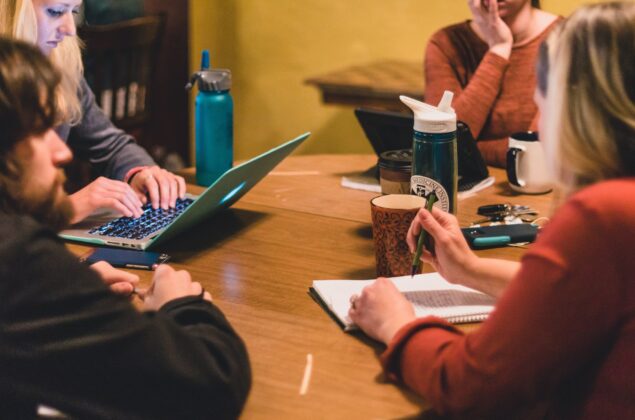 Students work together at a coffee shop on their laptops.