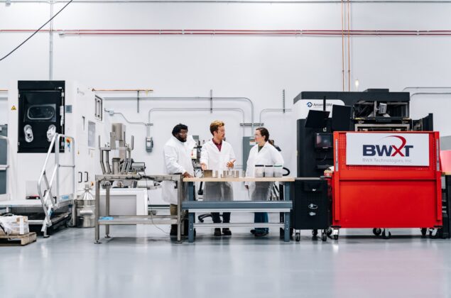 Young employees in lab coats in a warehouse.