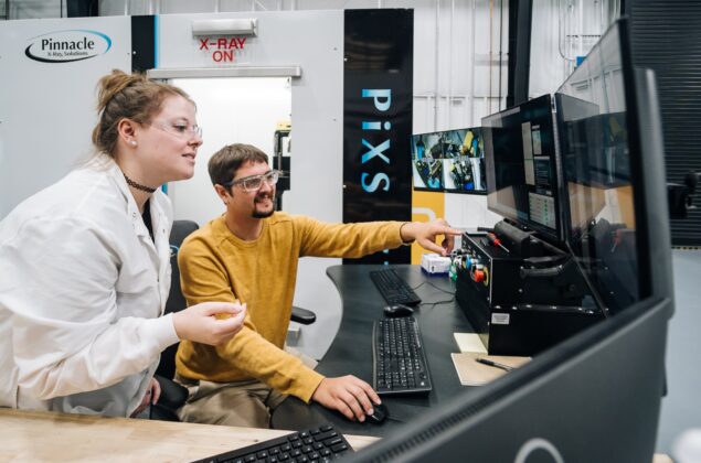 Two technicians analyzing data at an X-ray inspection station.